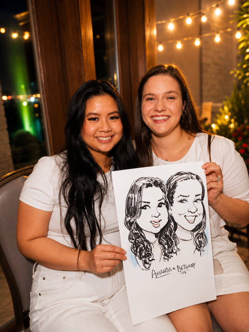 Two women holding a duo caricature at an evening community gathering with string lights